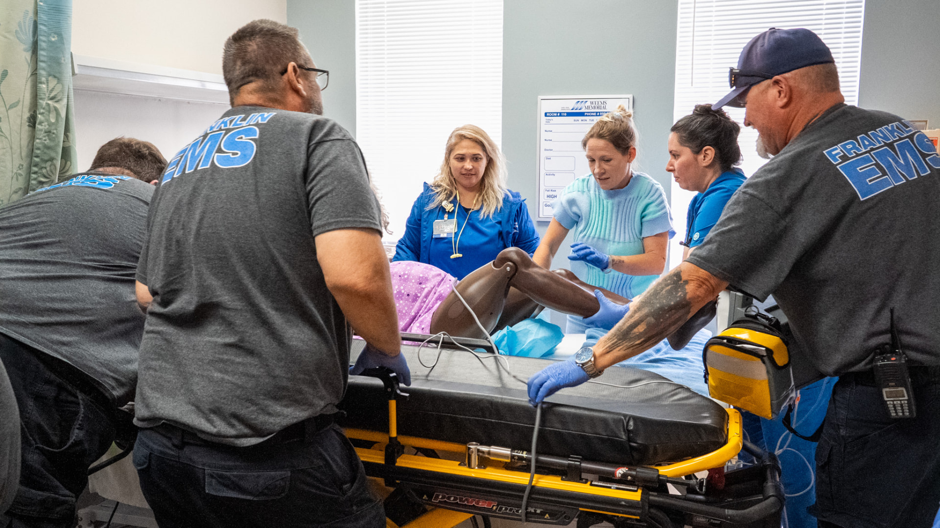 EMS and hospital nursing staff transferring a training manikin onto a stretcher during OB training
