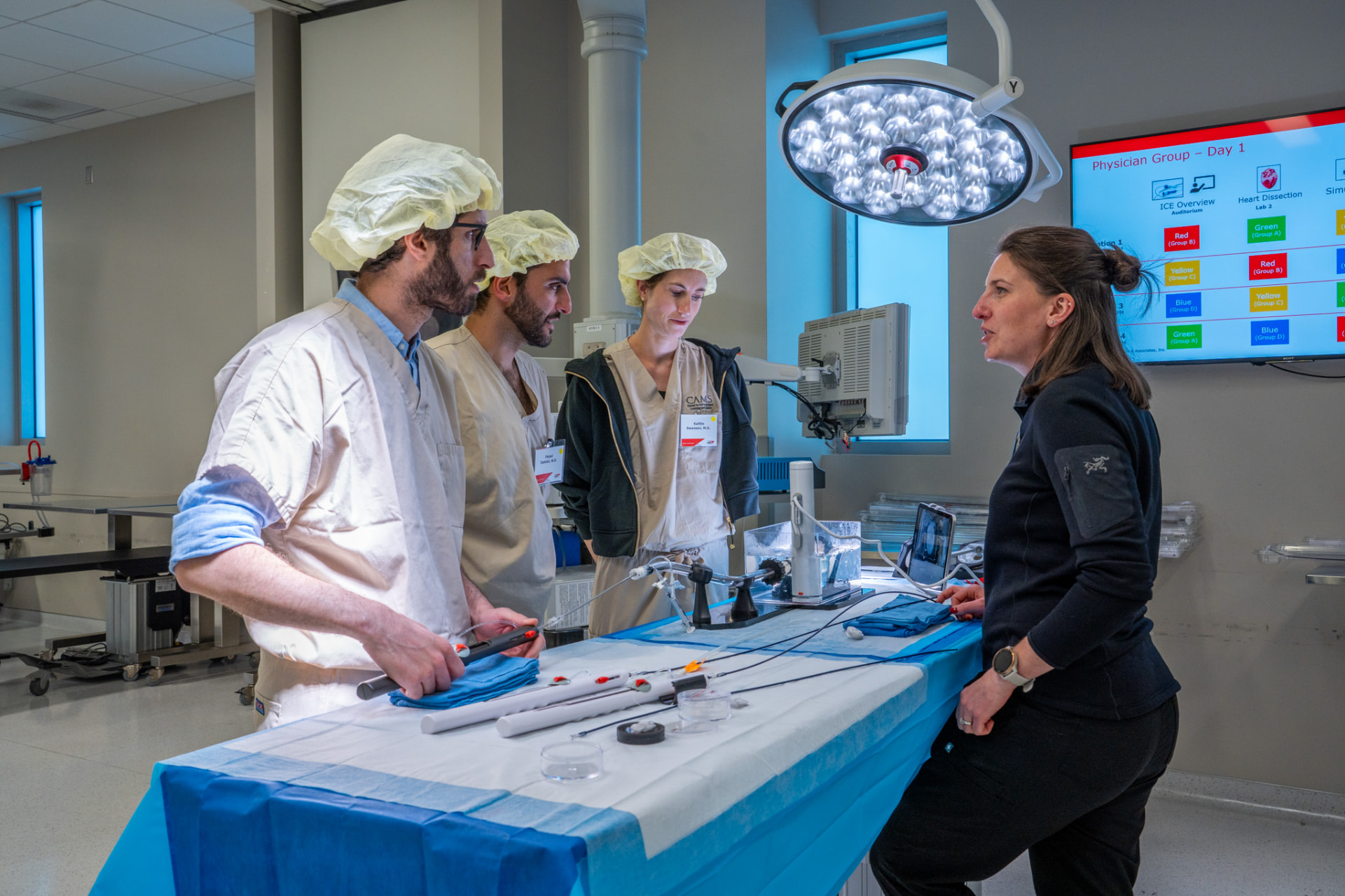 Instructor teaching three fellows around a simulation table during an annual fellows workshop
