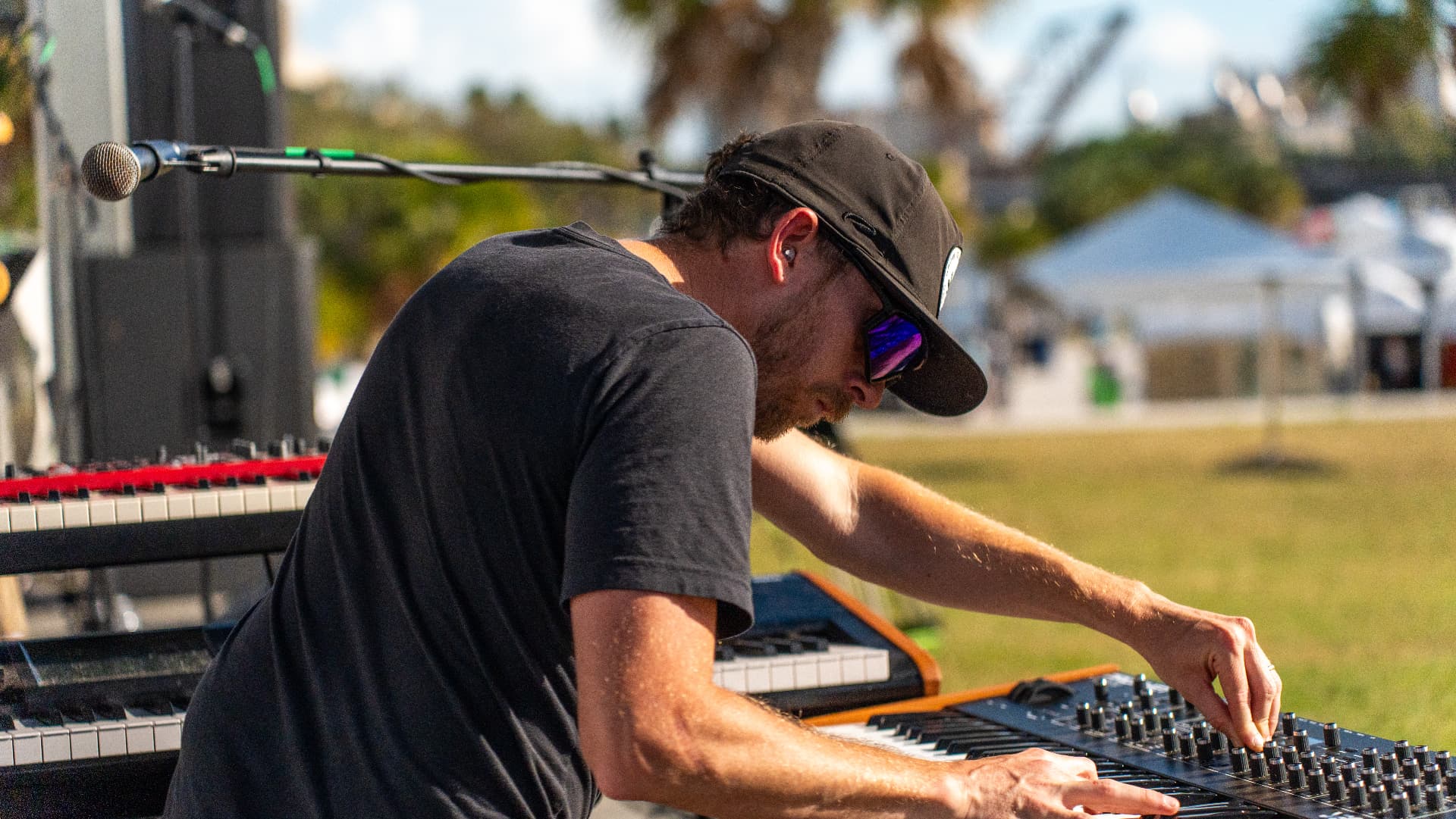 Ajeva's keyboardist leaning over a synth and stacked keyboards mid-performance