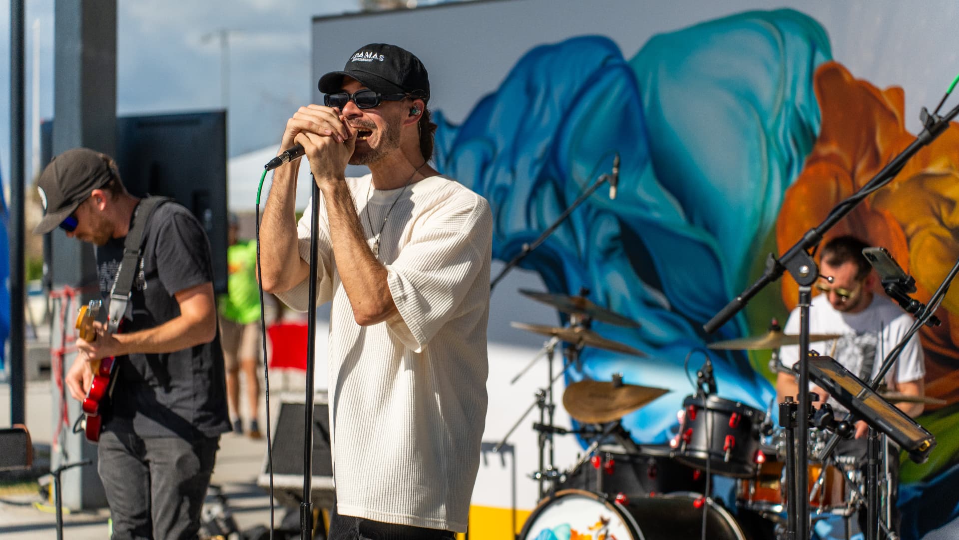 Ajeva's vocalist singing into a handheld mic during a Gasparilla Festival of the Arts set