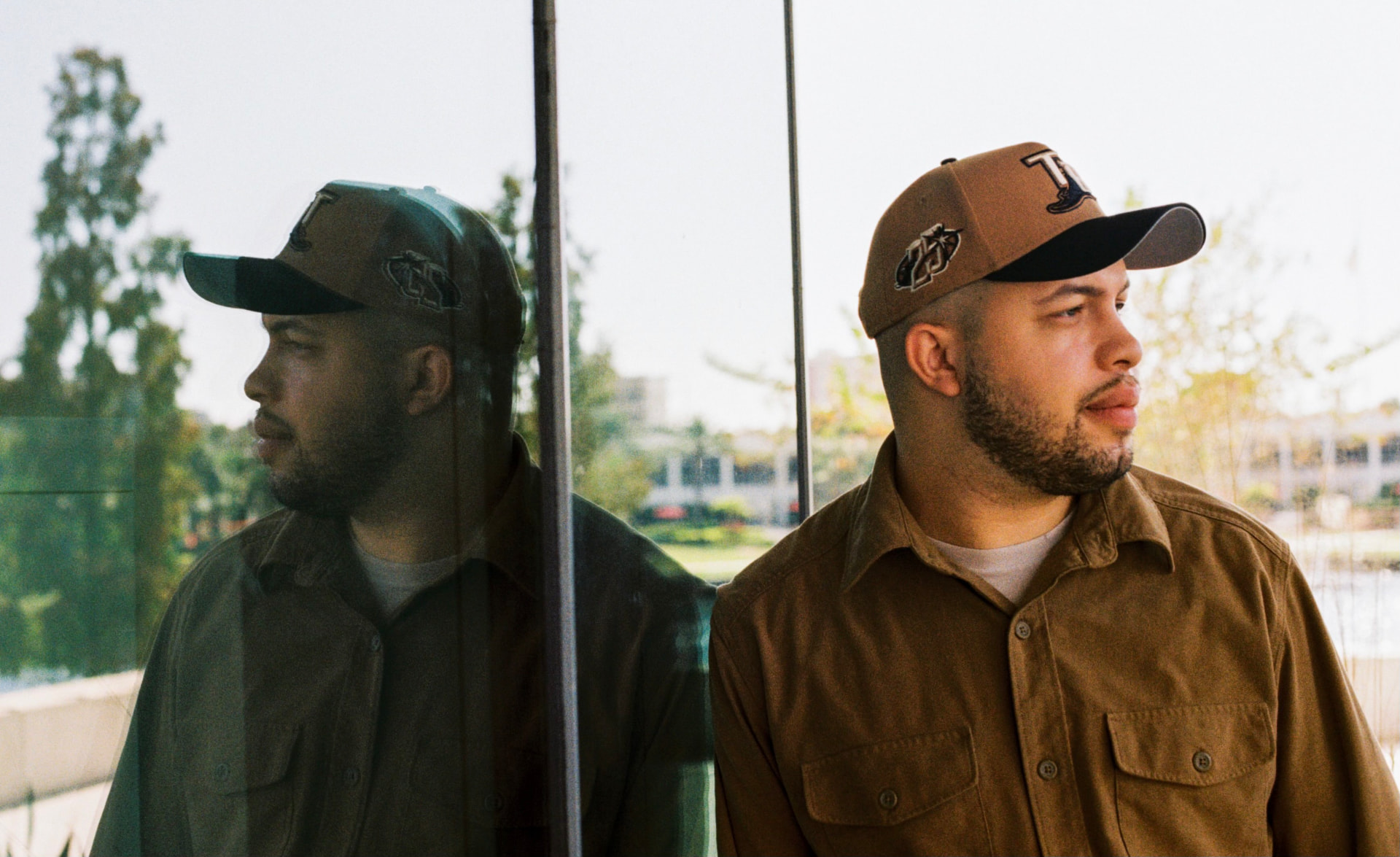 Film portrait of a man in a brown work shirt and cap reflected in glass panels