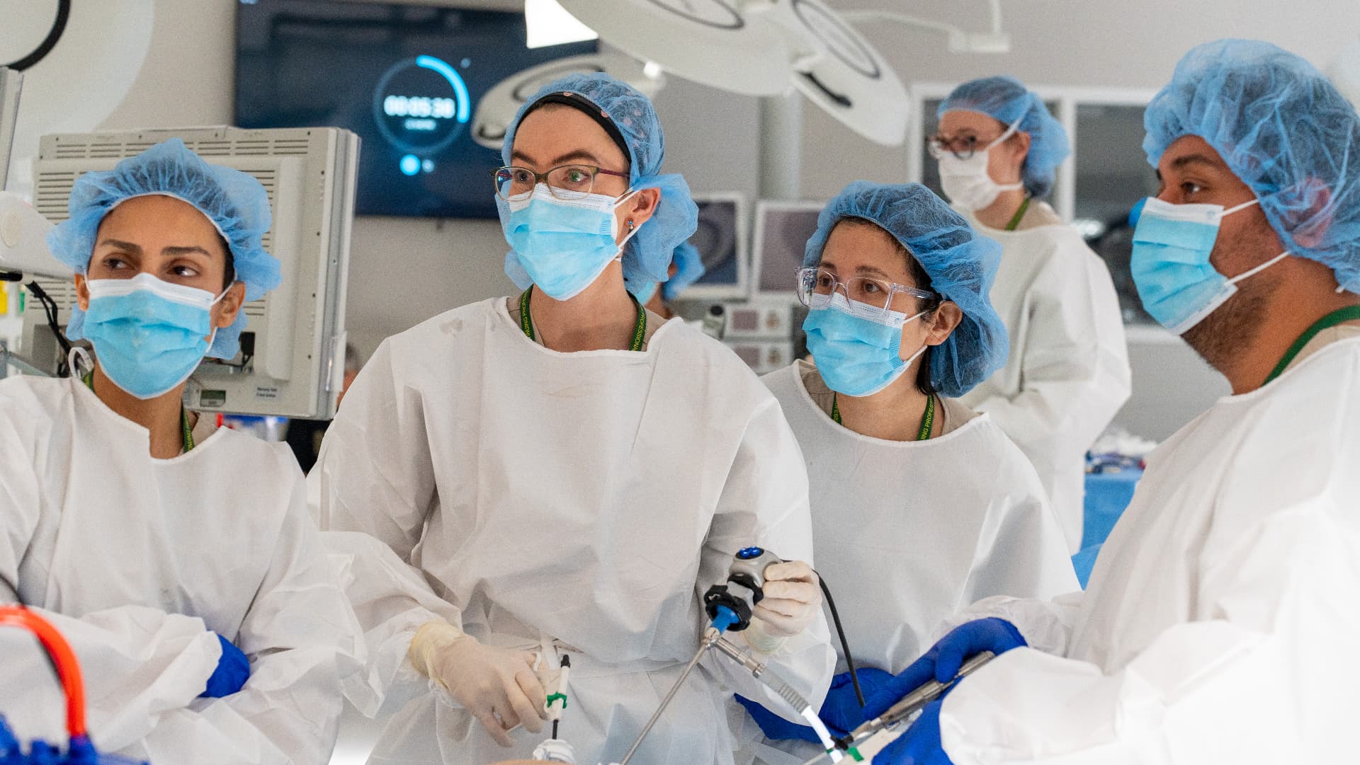 Course participants in surgical gowns practicing laparoscopic instrument handling in a training OR