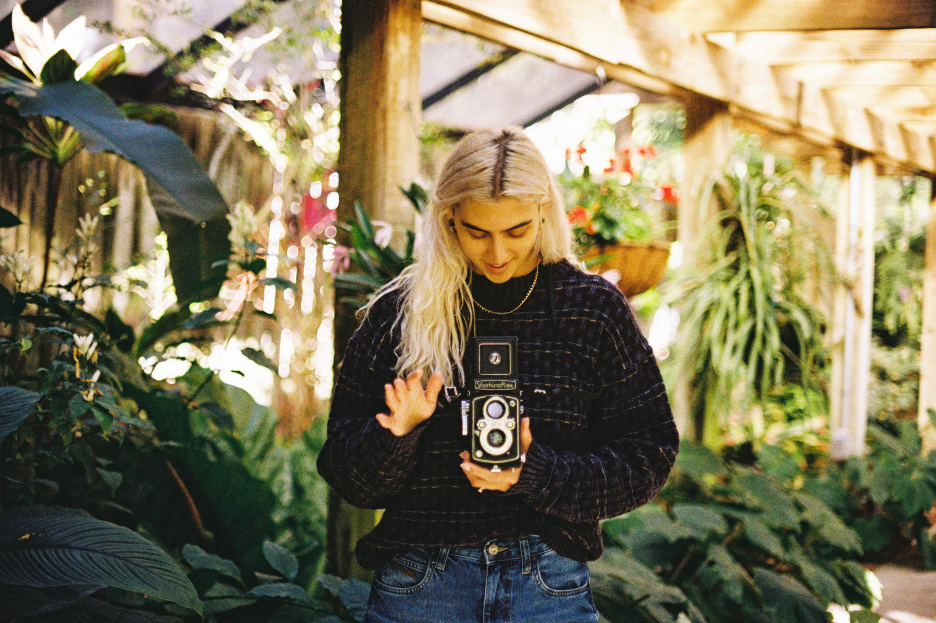 Portrait of a person holding a vintage Yashicaflex camera inside a plant nursery